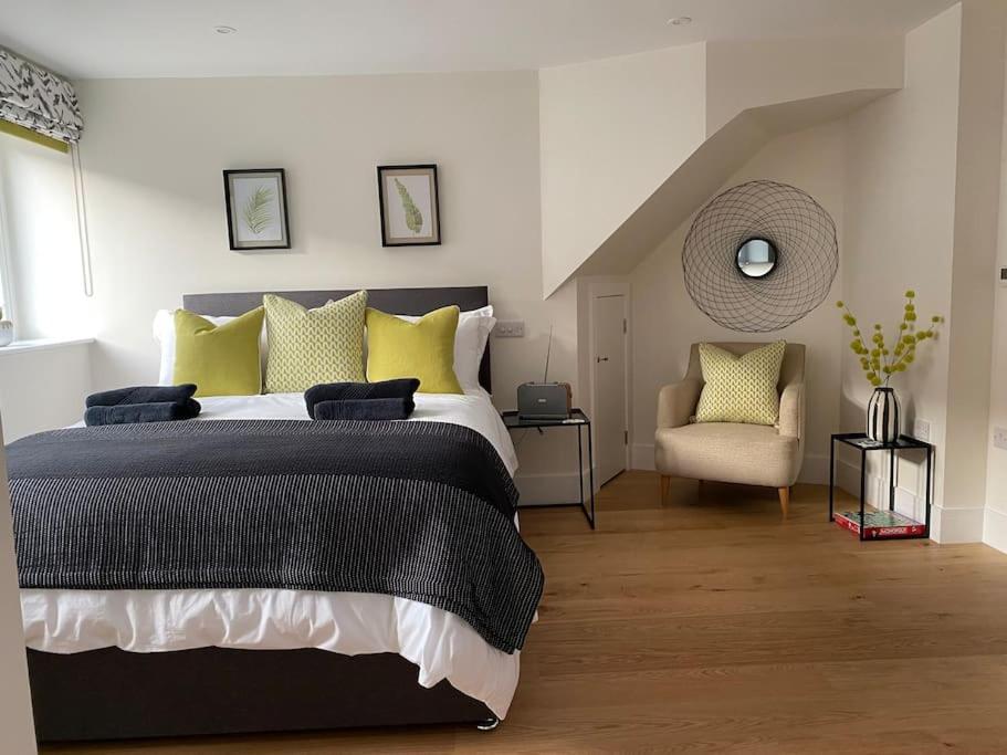 a bedroom with a bed with yellow pillows and a chair at New studio apartment - minutes walk to Cathedral in Salisbury