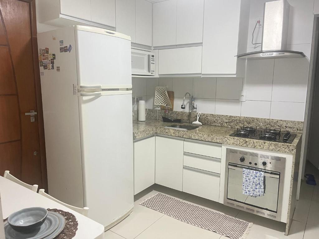 a kitchen with white cabinets and a refrigerator at Ed forte da Praia in Guarapari