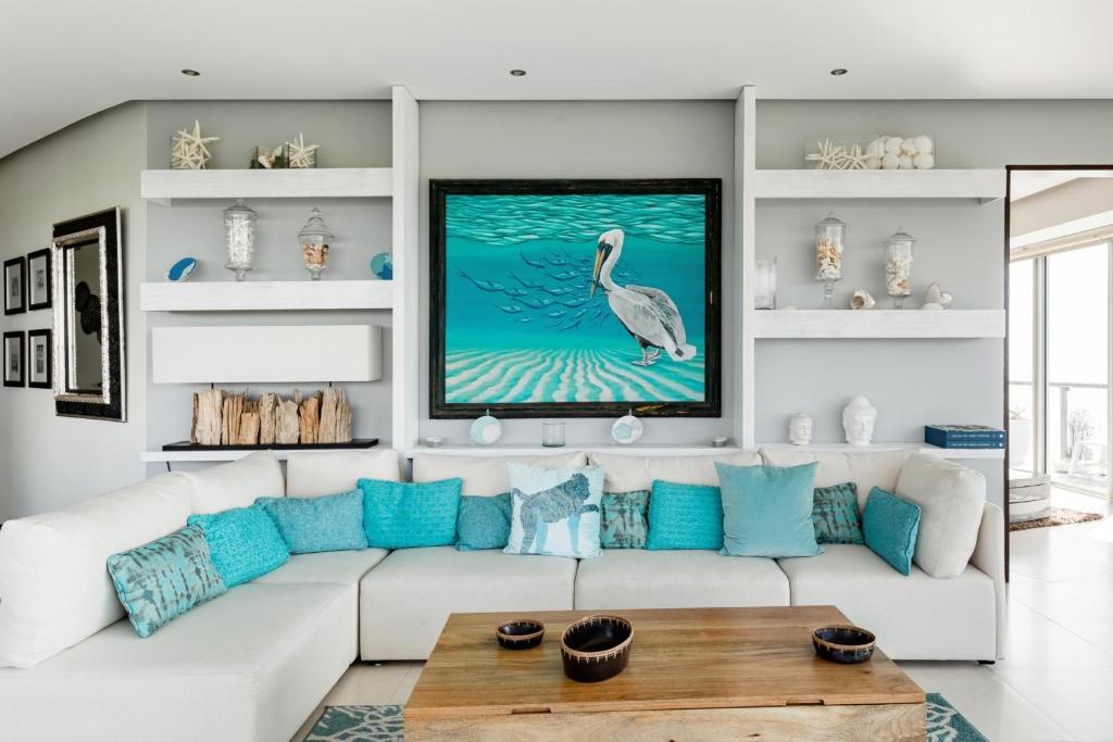 sala de estar con sofá blanco y almohadas azules en Espectacular Departamento de lujo frente al mar, en Cancún
