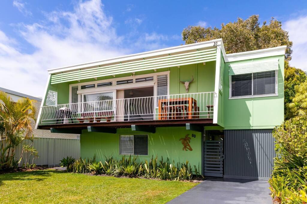 a green house with a balcony at BEACHED @ YAMBA (water views, dog friendly, air con) in Yamba