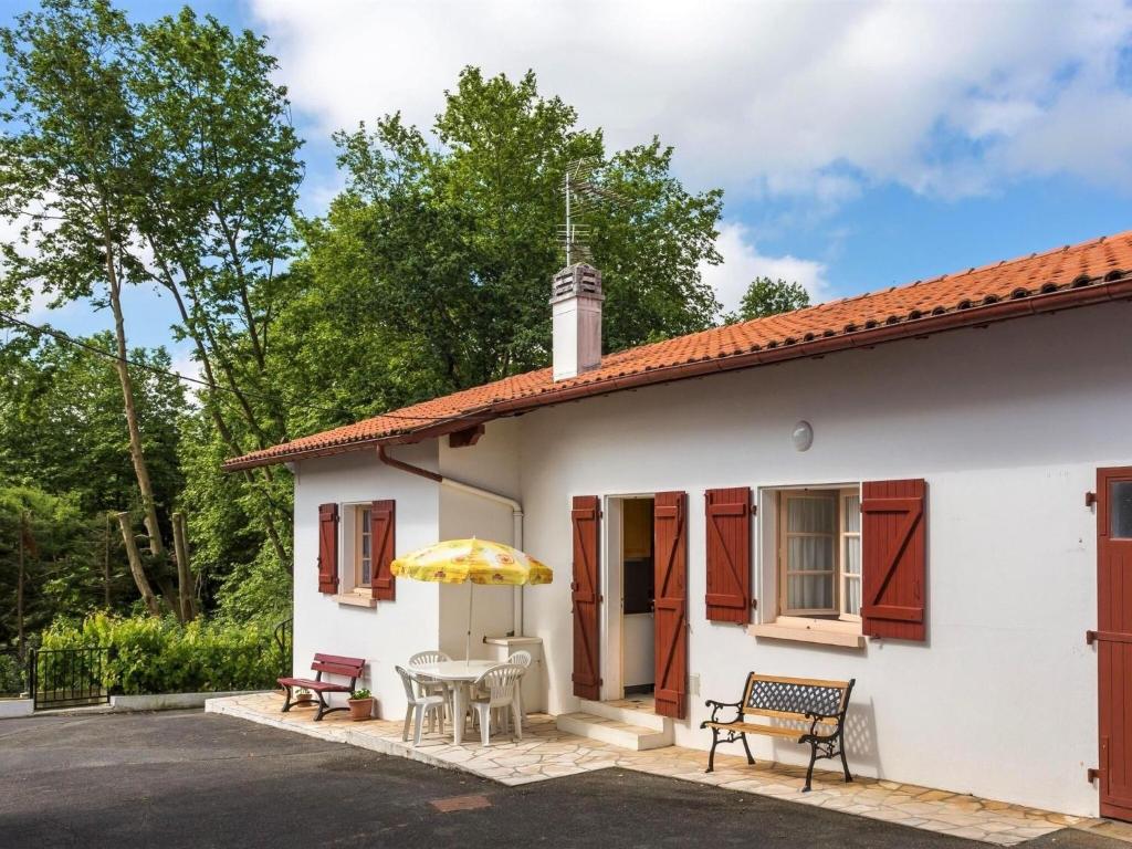 a white house with a table and a yellow umbrella at Basque style house 15 min from Bidart beaches in Arcangues