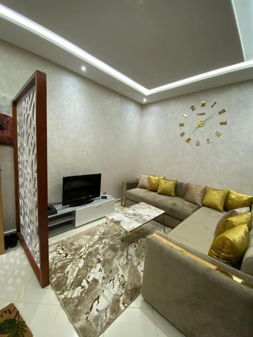 uma sala de estar com um sofá e um relógio na parede em Geil Wohnung in Agadir Zentrum Haut founty em Agadir