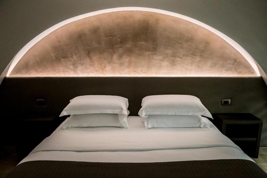 a bed with an arch over it with two pillows at ARCADIAN suite&rooms in Turin