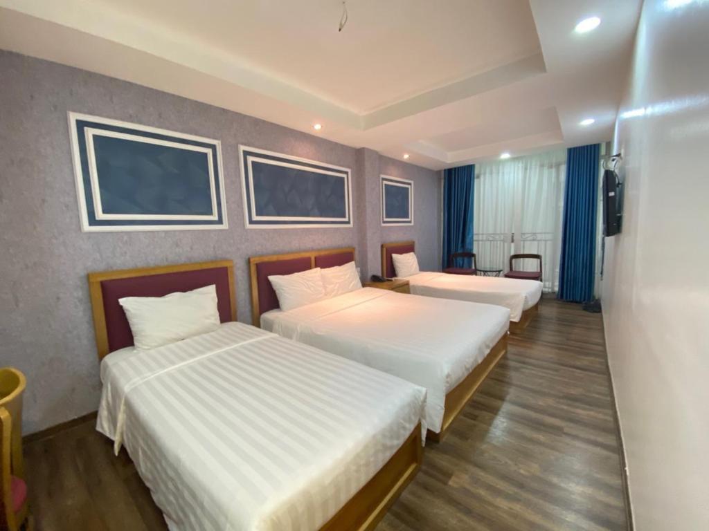a hotel room with three beds and a television at Holiday Suites Hotel & Spa in Hanoi