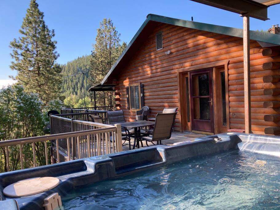 a log cabin with a pool and a table and chairs at Hummingbird Hill Resort: Hot Tub, Views, Wildlife, 3D movies, Hiking, Bikes, Sleds, Games, Kids & Pets Love It in Naches