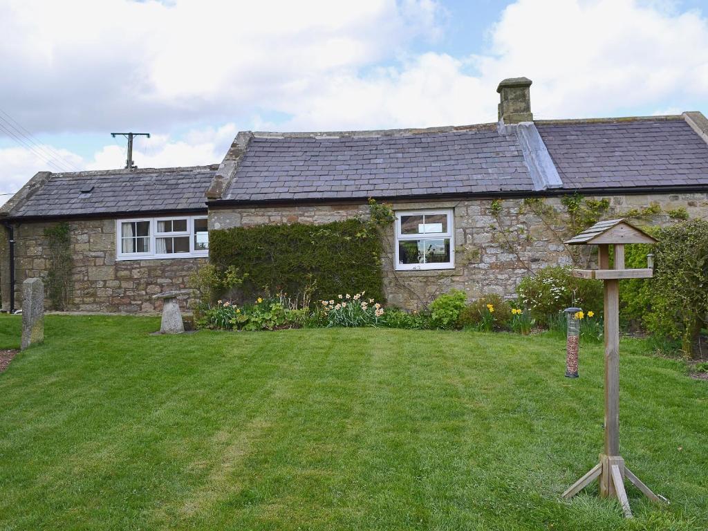 a stone house with a yard in front of it at Garden Cottage in Edlingham