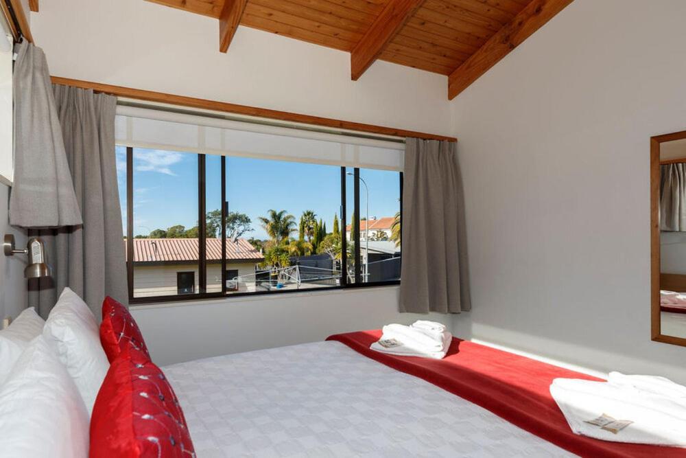 1 dormitorio con cama y ventana grande en Unit 2 Kaiteri Apartments and Holiday Homes, en Kaiteriteri