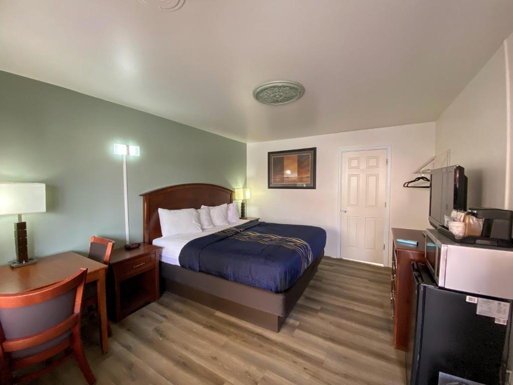 モアブにあるInca Inn Moabのベッド、デスク、テレビが備わるホテルルームです。