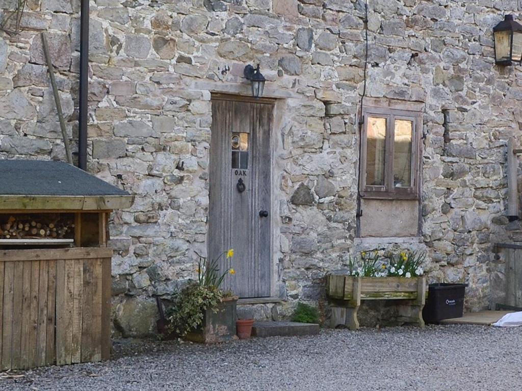 a stone building with a wooden door and a window at Oak Barn Cottage in Trefonen