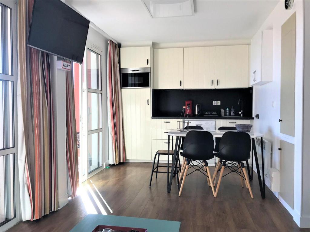 une cuisine avec une table et des chaises dans une pièce dans l'établissement Appartement 3 pièces avec grande terrasse, climatisation, piscine et parking - FR-1-504-659, à Saint-Raphaël