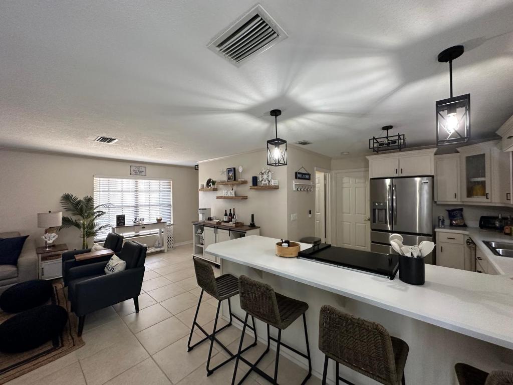 a kitchen with a large counter and chairs in it at Three Treasures Beach House in New Smyrna Beach