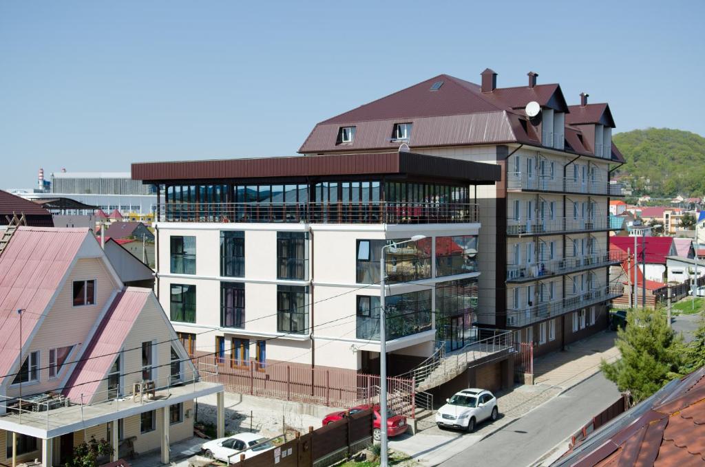 ein weißes Gebäude mit einem braunen Dach auf einer Stadtstraße in der Unterkunft Boutique Hotel Tamara in Adler
