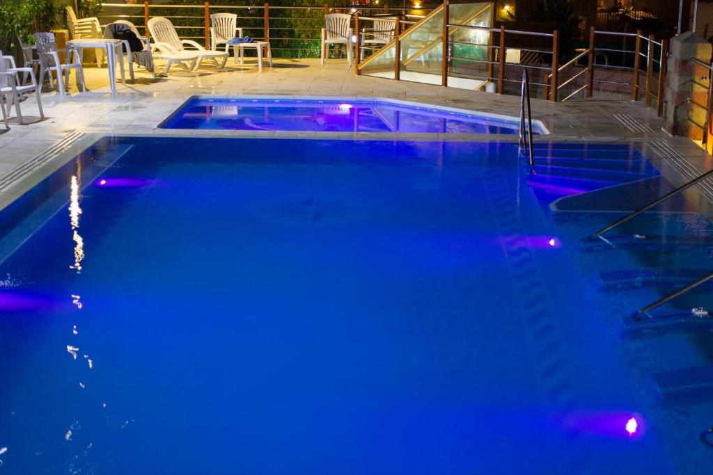 una piscina con luces azules en un patio en Hotel Teomar en Villa Gesell