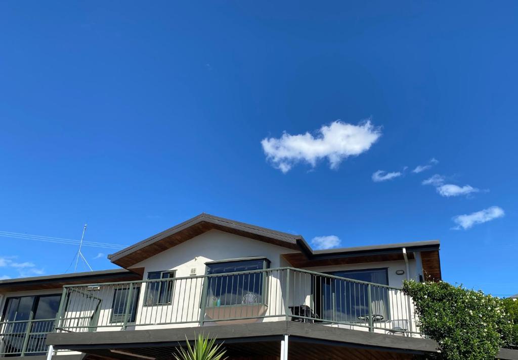 a house with a balcony and blue sky at Unit 12 Kaiteri Apartments and Holiday Homes in Kaiteriteri