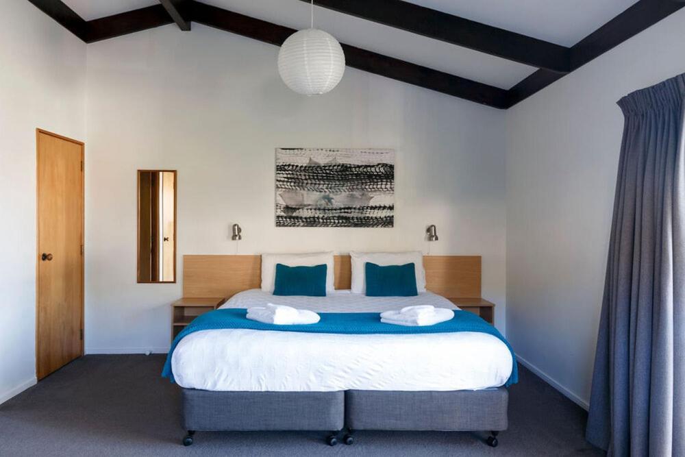 a bedroom with a large bed with blue pillows at Unit 4 Kaiteri Apartments and Holiday Homes in Kaiteriteri