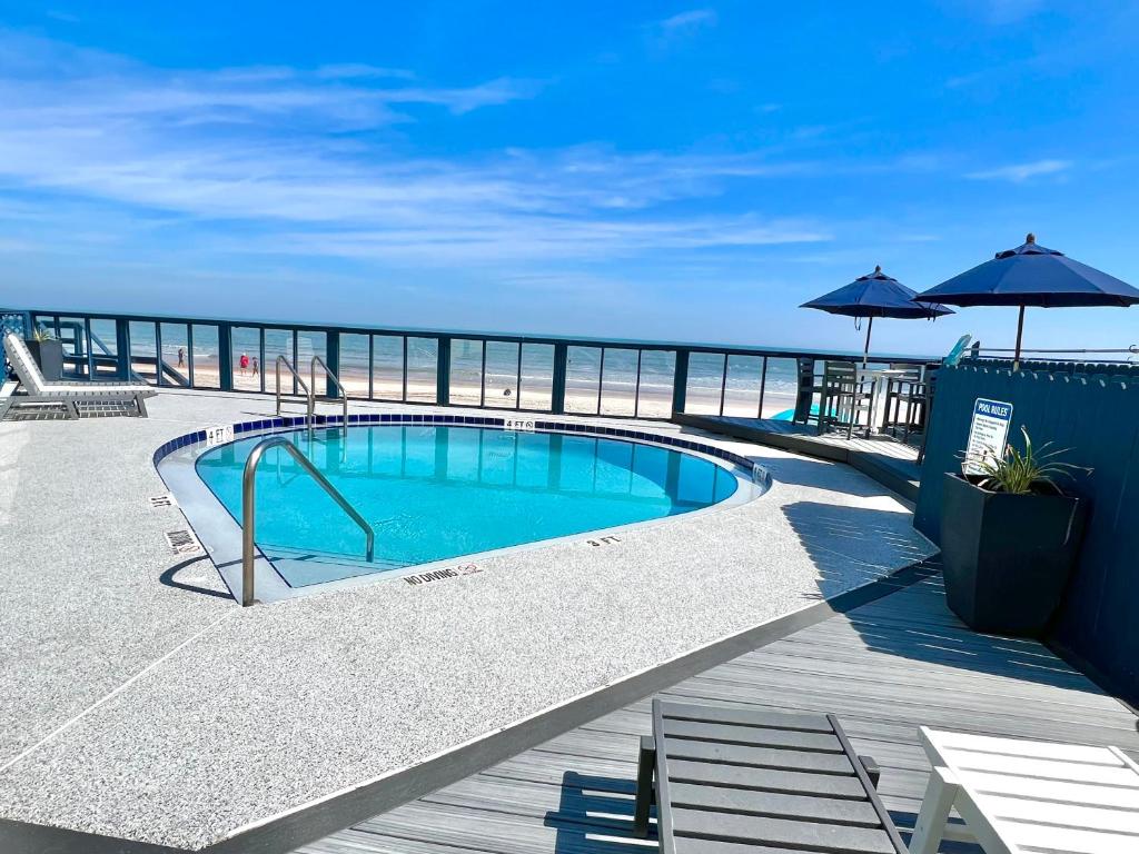 a swimming pool on a deck next to the ocean at Just Beachy -Ocean View at Symphony Beach Club in Ormond Beach