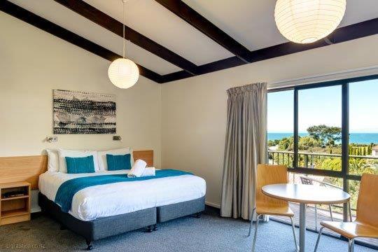 a bedroom with a bed and a view of the ocean at Unit 6 Kaiteri Apartments and Holiday Homes in Kaiteriteri