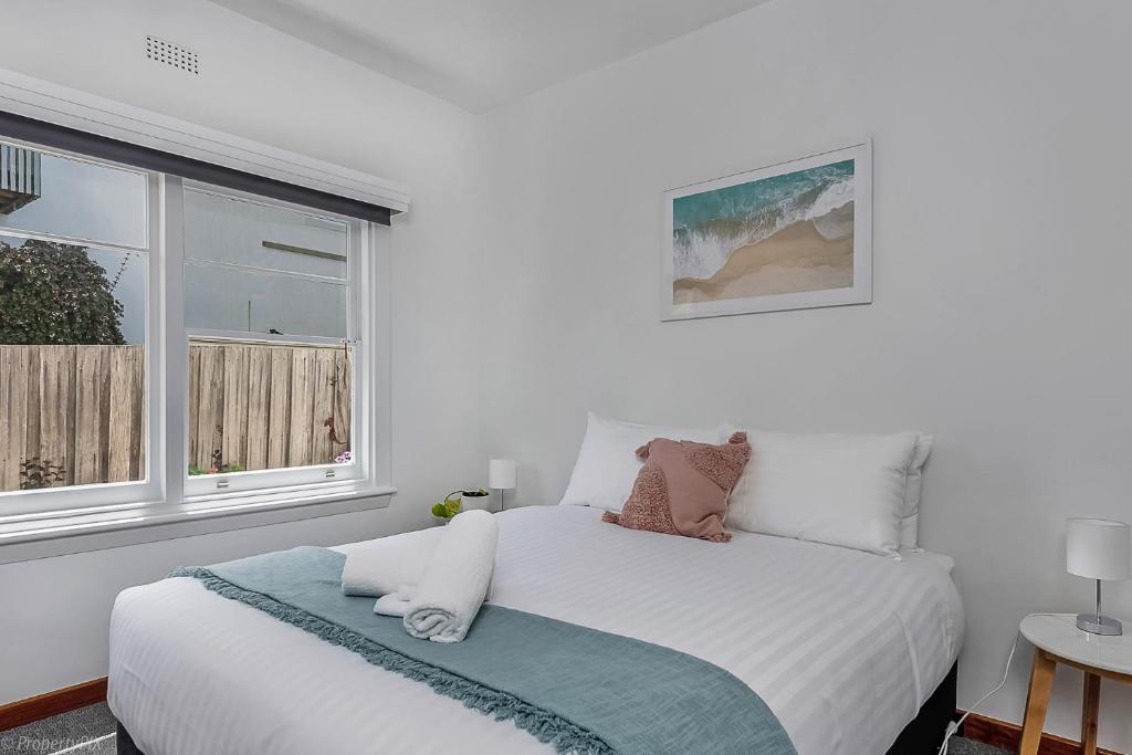 a white bedroom with a bed and two windows at Bella Vista on Beach in Hobart