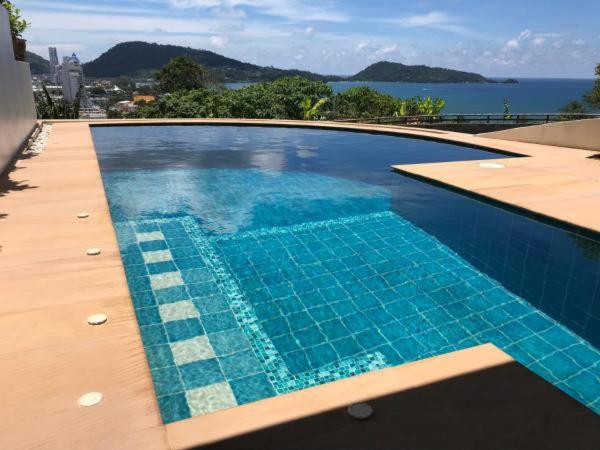 a blue swimming pool with a view of the water at Andaman Hill Pool Seaview in Patong Beach