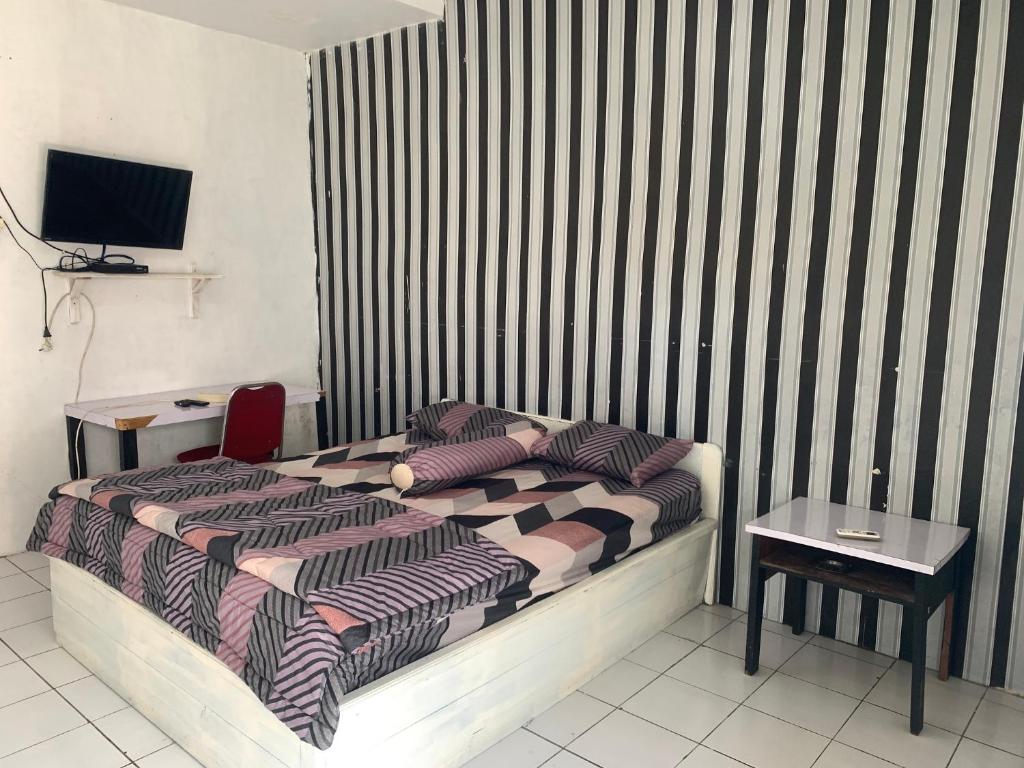 Schlafzimmer mit einem Bett, einem Tisch und einem TV in der Unterkunft ASOKA GUEST HOUSE in Pangkalan Bun