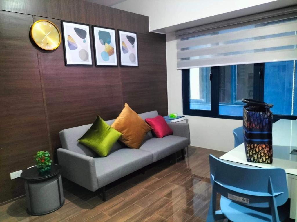 a living room with a couch with colorful pillows at Air Residences Staycation in Manila