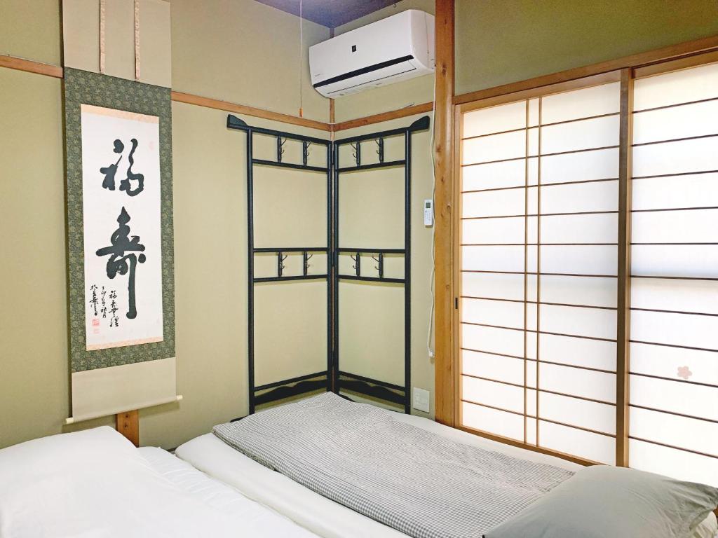 um quarto com uma cama num quarto com uma janela em 花楓舎-Sakura & Maple Guest House-ゲストハウス em Quioto