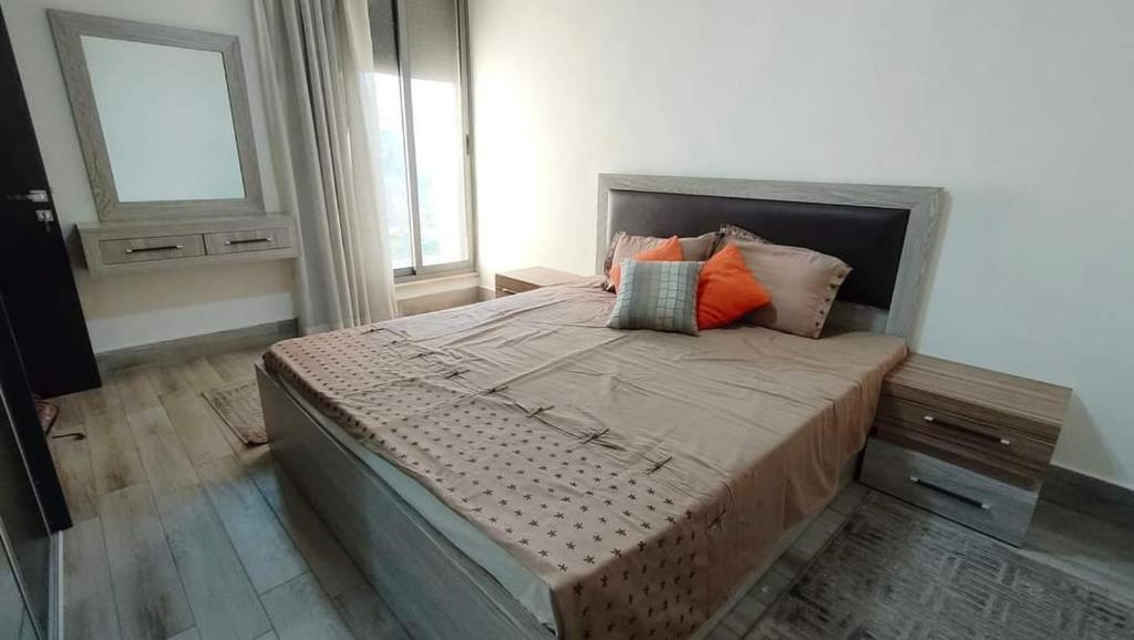 a bedroom with a bed with pillows and a window at Aljood apartment in Amman