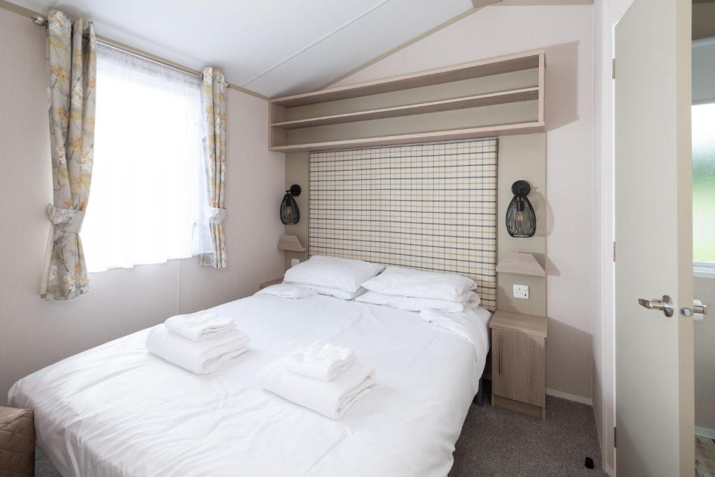 a bedroom with a white bed with white towels on it at Luxury Holiday Home Sleeps 6 Pet Friendly in St Austell