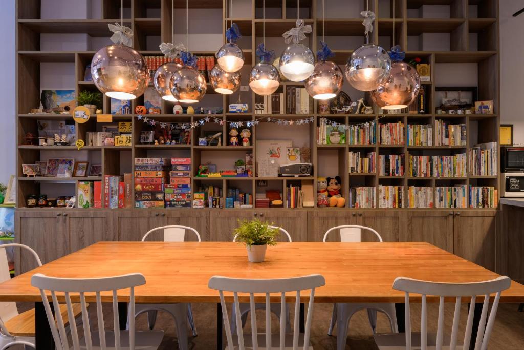 a wooden table with chairs and lights above it at On My Way Hualien Hostel in Hualien City