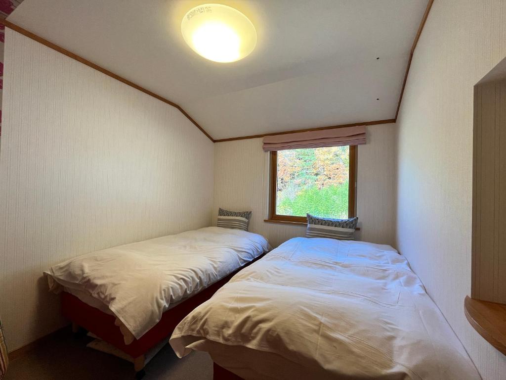 two beds in a small room with a window at La Posada in Fujikawaguchiko