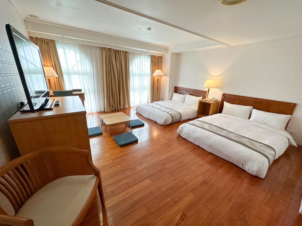 a hotel room with two beds and a television at Grand Boss Hotel in Yilan City