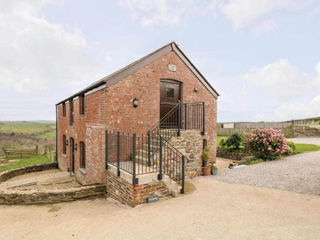 a brick building with a door and a gate at Castle Dore Barn in Par