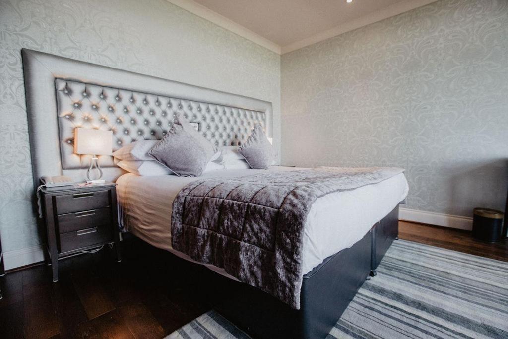 a bedroom with a large bed and a night stand with a lamp at The Woolacombe Bay Hotel in Woolacombe