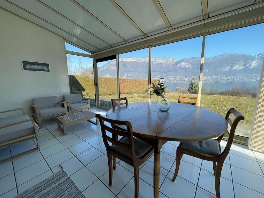 comedor con mesa y sillas y ventana grande en La Roselière Sud, vue lac & jardin, en Sévrier