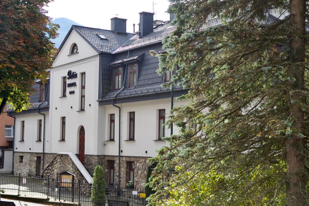 a large white house with a black roof at Hotel Patria Zakopane Centrum in Zakopane