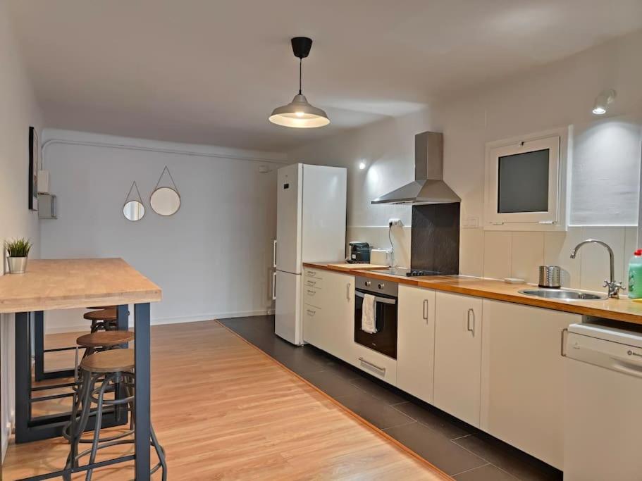 una cocina con armarios blancos y una mesa. en Cute apartment Sant Adria beach, en Sant Adrià de Besòs