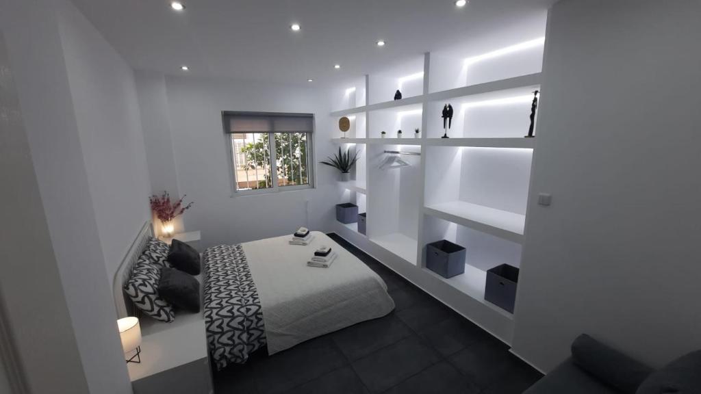 a white room with a bed and a table and shelves at Glyfada Vacation Apt in Athens