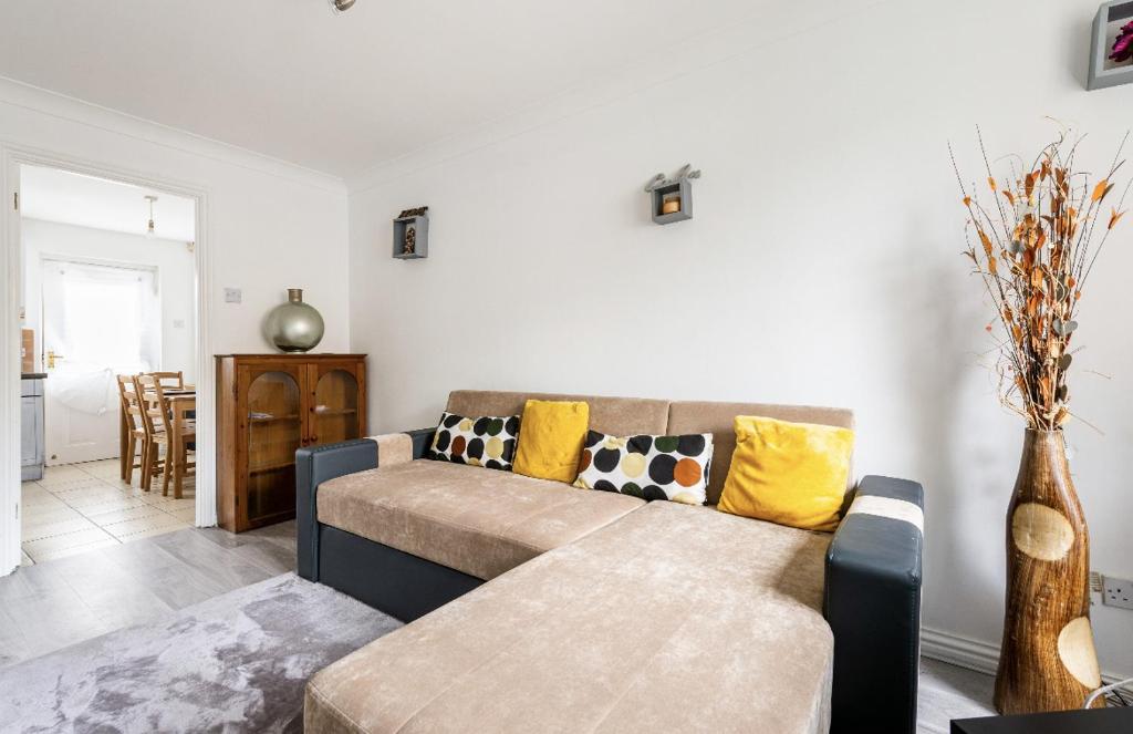 a living room with a brown couch and yellow pillows at Beautiful Comfortable Double Room in Thamesmead