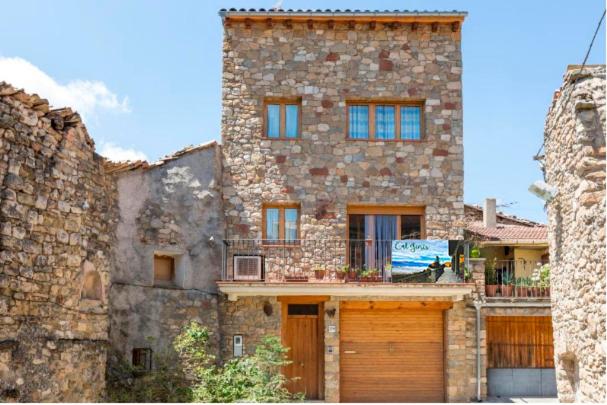 un gran edificio de piedra con dos puertas de garaje delante de él en Cal Ginés en Llimiana