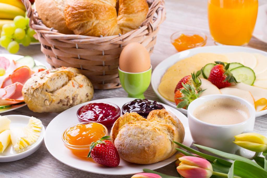 uma mesa coberta com pratos de alimentos para pequeno-almoço e frutas em Hotel am Schlosspark Superior - Adults Only Hotel em Putbus