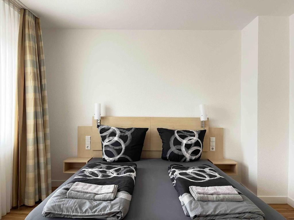 Un dormitorio con una cama con almohadas blancas y negras. en Schöne Apartments I private Parkplätze I home2share, en Münster