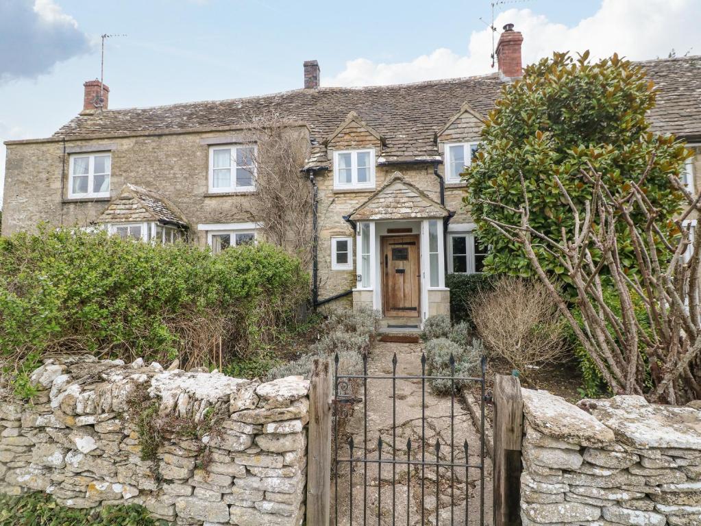 an old stone house with a gate and a stone wall at Brooklands in Chedworth