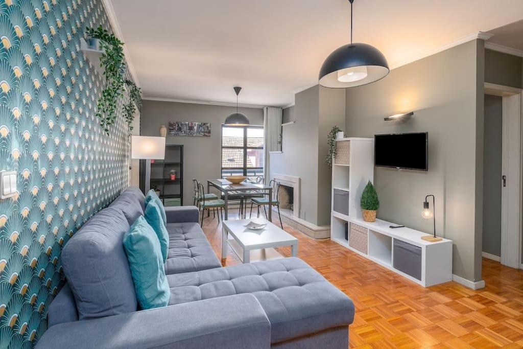 uma sala de estar com um sofá azul e uma mesa em RenFeb23Boavista Deluxe with private parking no Porto
