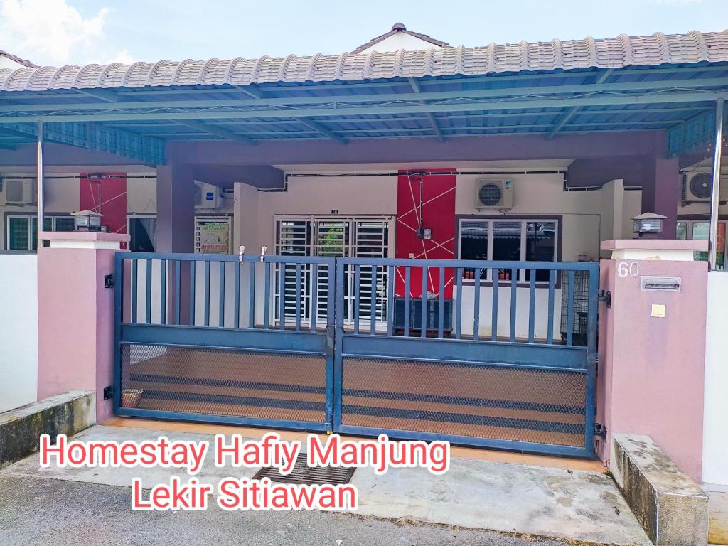 a house with a blue fence and a gate at Homestay Hafiy Manjung Lekir Sitiawan in Lekir