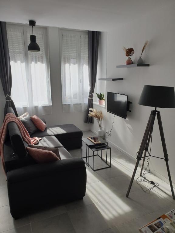 sala de estar con sofá negro y TV en Maison complete, jusqu a 6 personnes en Le Cateau