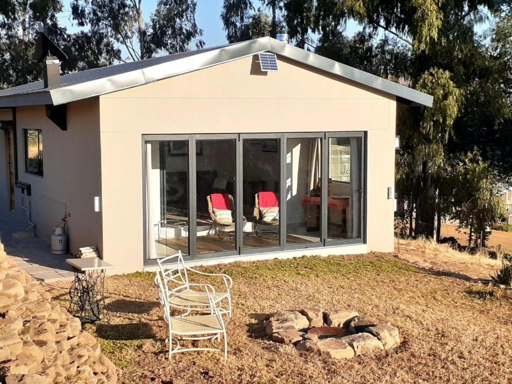a house with glass doors and a chair in the yard at Sunset View Self catering Cottage in Underberg