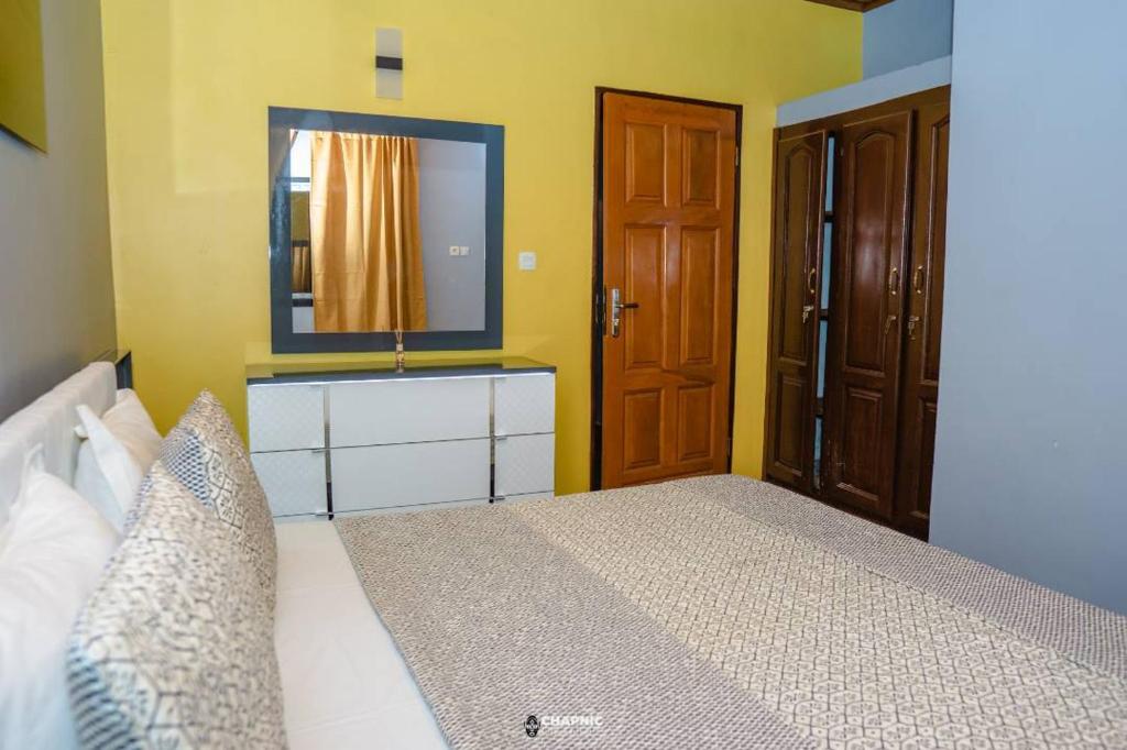 a bedroom with a bed with a mirror and a door at At Home Lisda in Yaoundé
