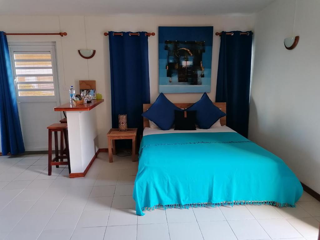 1 dormitorio con cama azul y cortinas azules en Terre et Mer - Studios - Ile Maurice, en Rivière Noire