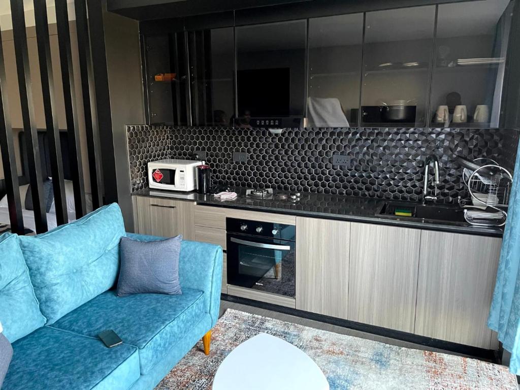 a living room with a blue couch and a kitchen at PARANAIS APARTMENT 2 in Nairobi