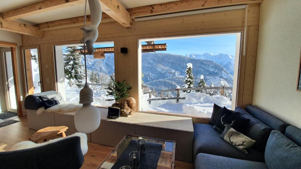 a living room with a large window with a mountain view at Chalet Baumfuchs direkt an der Talabfahrt Belalp in Blatten bei Naters